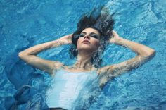 a woman is floating in the water with her hair up