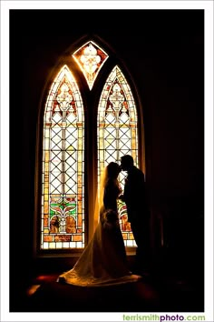 a bride and groom standing in front of a stained glass window at the end of their wedding day