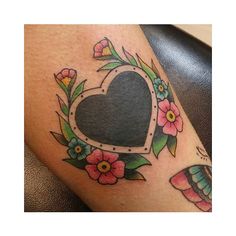 a woman's thigh with flowers and a heart shaped frame on the side of her leg