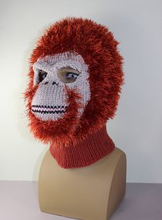 a knitted red and white monkey mask on a mannequin's head