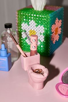 a pink toilet sitting on top of a table next to a green box and other items