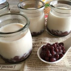 three jars filled with milk and beans next to a spoon