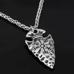 a silver necklace with an open heart and compass on the front, sitting on a black surface