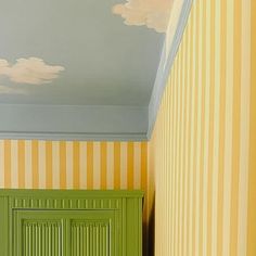 an empty hallway with green doors and yellow striped wallpaper on the walls, along with a painted ceiling