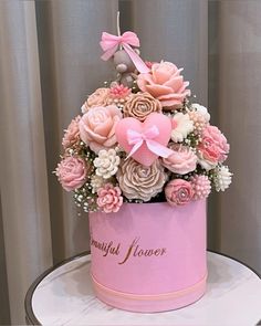 a pink hat box with flowers and a teddy bear on the top is sitting on a table