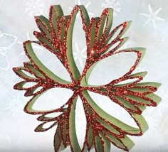 an ornament made out of paper with red glitters on it and snowflakes in the background