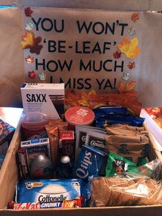 an open box filled with snacks and other items next to a sign that says you won't be leaf how much i miss ya