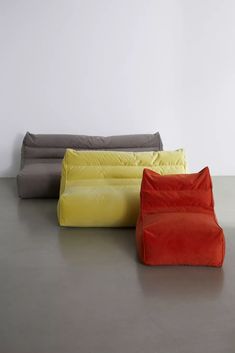 four different colored bean bags sitting next to each other on the floor in front of a white wall