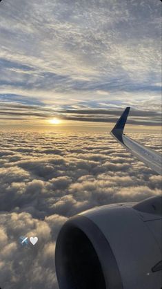 an airplane wing flying above the clouds at sunset