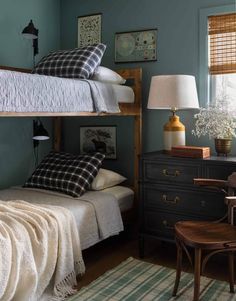 a bedroom with two bunk beds and a desk in front of the bed has a lamp on it