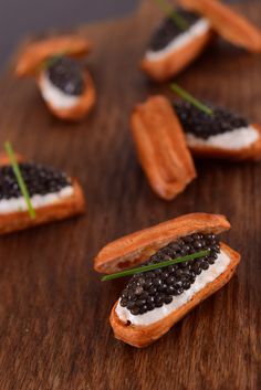 small crackers with black and white toppings are on a wooden table, ready to be eaten