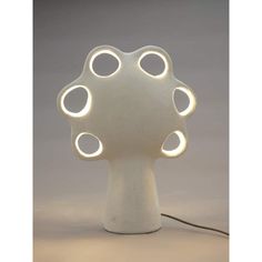 a white table lamp with multiple circles on it's base and a cord running through the middle