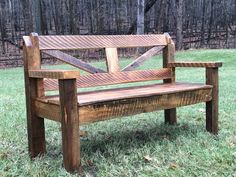 a wooden bench sitting on top of a lush green field next to a wooded area