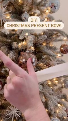 a hand is pointing at a christmas tree with the words diy christmas present bow on it