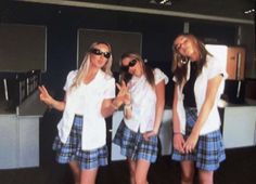 three girls in plaid shorts and white shirts posing for the camera with their hands up