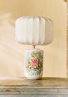 a white lamp sitting on top of a table next to a vase filled with flowers