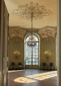 an ornately decorated room with chandelier and chairs in front of a large window