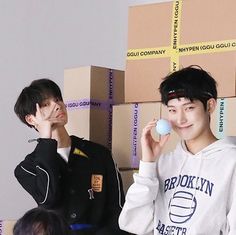 two young men standing next to each other in front of boxes and one holding a ball