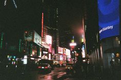 a city street at night with cars and billboards