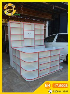 two white shelving units with red trims on the top and bottom, in front of a van