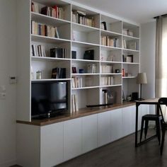 a living room filled with furniture and a flat screen tv on top of a book shelf