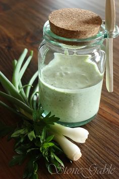 a jar filled with green liquid next to some vegetables