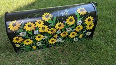 a painted mailbox in the grass with sunflowers and daisies on it