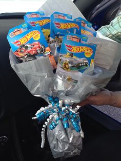 a person holding a bunch of hot wheels wrapped in plastic wrapper and some toys