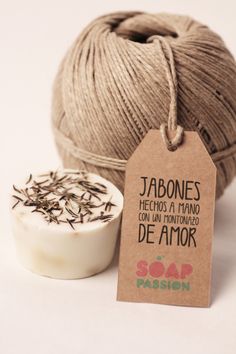 a ball of yarn next to a small bowl of soap and a tag that says jabones