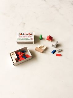 an assortment of wooden toys sitting on top of a white counter next to a box