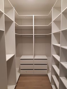 an empty walk in closet with white shelves