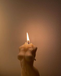 a candle that is lit up in the shape of a woman's body on a table