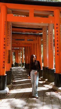 a woman standing in front of an array of orange tori toris with writing on them