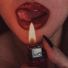 a woman holding a lighter in her mouth with the light on it's side