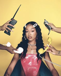 a woman sitting on the ground with hair dryers in her hands and two other women holding phones