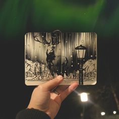 a person holding up a card with an image of a deer on it in front of green lights