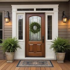 a front door with potted plants and a wreath on it