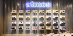 the inside of a shoe store with many shoes on display in front of a neon sign that reads atmos