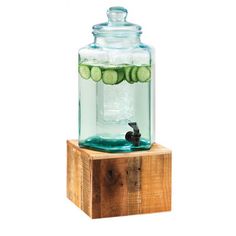 a glass jar filled with cucumbers sitting on top of a wooden block