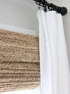 the curtain rod is attached to the window in front of the white drapes with black hardware