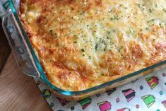 a casserole dish with cheese and parsley in it on a wooden table