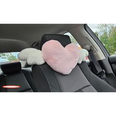 two stuffed animals in the back seat of a car with pink and white heart pillows