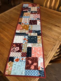 a table runner made out of patchwork fabric on top of a wooden dining room table