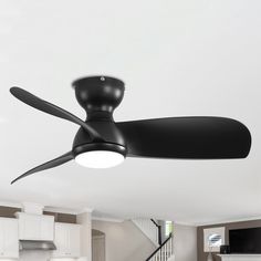 a black ceiling fan in a living room with white walls and stairs leading up to the second floor