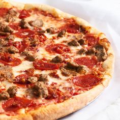 a pizza with meatballs and cheese on it sitting on top of a white napkin