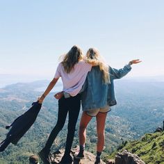 two women standing on top of a mountain with their arms around each other and the words friendship above them