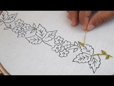 a person is stitching flowers on a white cloth with yellow thread in front of a wooden hoop