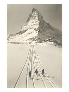 three people cross country skiing in front of a snow - capped mountain with ski tracks