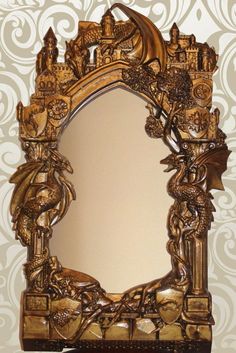 an ornate gold framed mirror on top of a wooden table next to a white wall