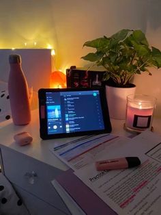 a tablet computer sitting on top of a desk next to a candle and some papers